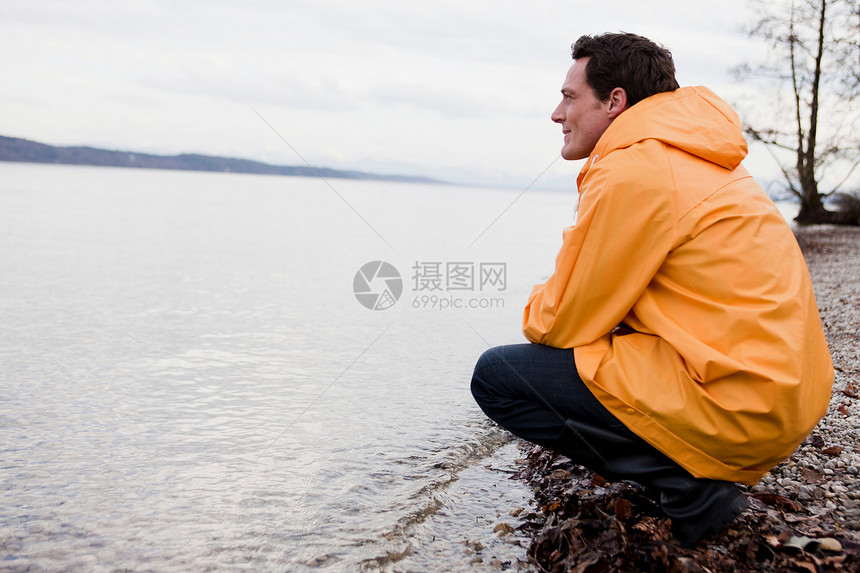 穿雨衣的人坐在岸边图片