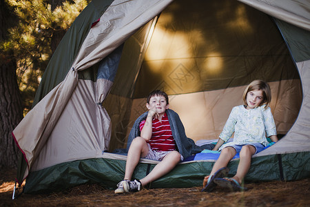 扎帐篷男孩孩子们坐在营地的帐篷里背景