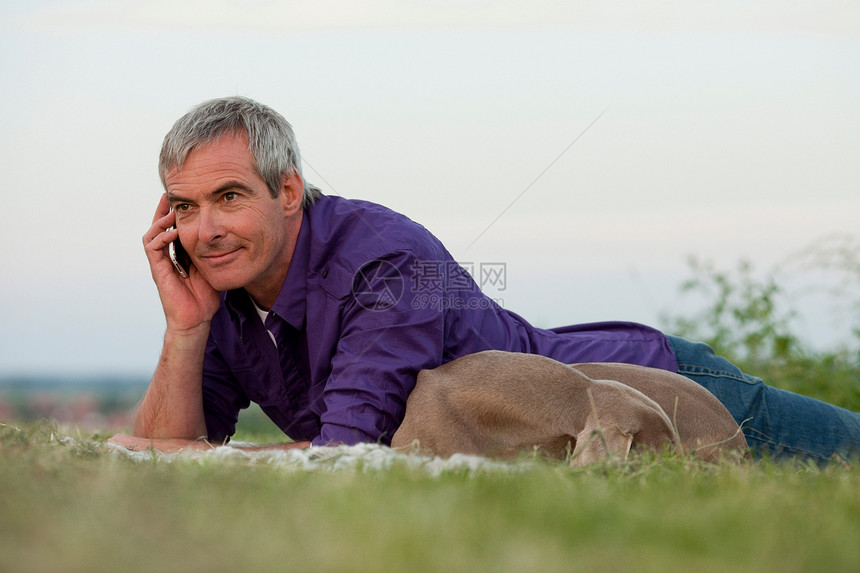 带着狗的男人在草地上打电话图片