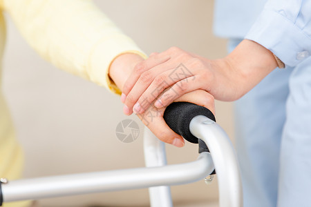 使用帮助护工扶着使用健步器的老奶奶锻炼身体特写背景