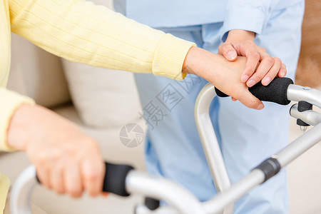 握着手机手护工扶着使用健步器的老奶奶锻炼身体特写背景