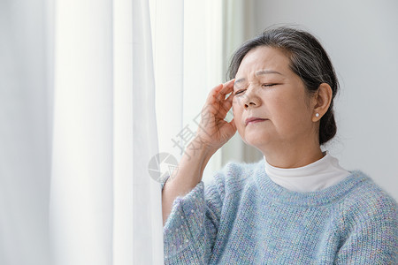 老人高血压靠在窗边头疼的女人背景