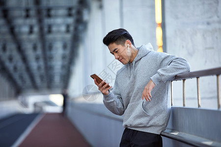 年轻运动男士户外使用蓝牙耳机通电话高清图片