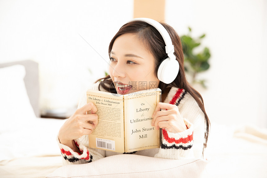 冬季居家青年女性带着耳机看书图片
