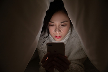 青年女性被窝熬夜玩手机图片