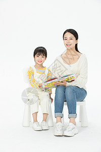 妈妈陪伴女儿坐在椅子上看童话故事书背景图片