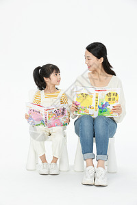 妈妈陪伴女儿坐在椅子上看童话故事书背景图片