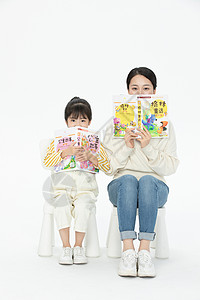 坐在椅子上看书妈妈陪伴女儿坐在椅子上看童话故事书背景