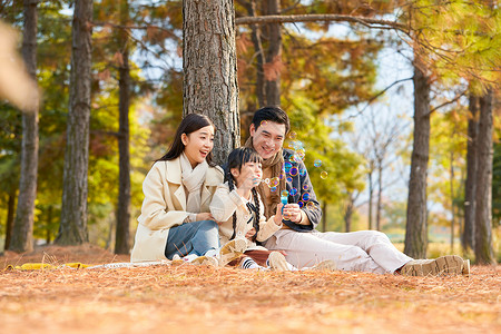 吹泡泡的女孩一家三口在公园吹泡泡背景