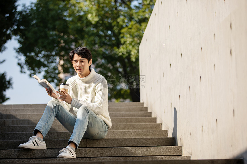 坐在楼梯上看书的青年男性图片