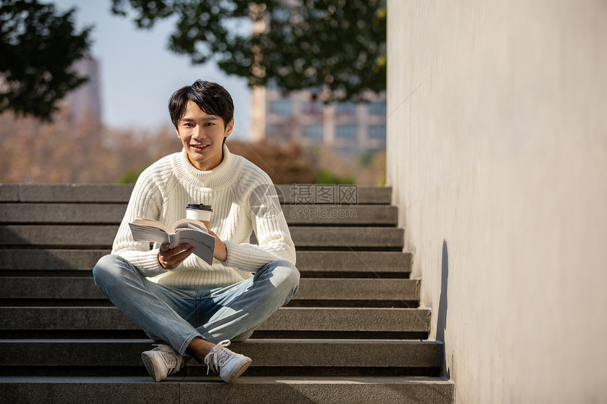 坐在楼梯上看书的青年男性图片