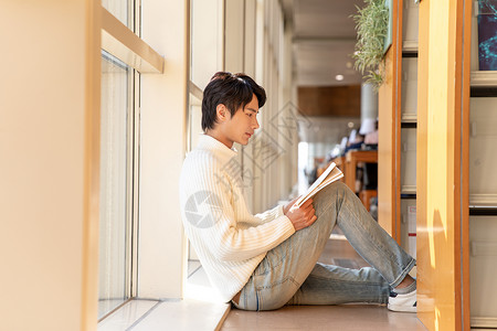 图书馆席地而坐看书的男性背景图片