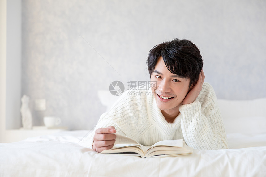 居家男性趴在床上看书图片