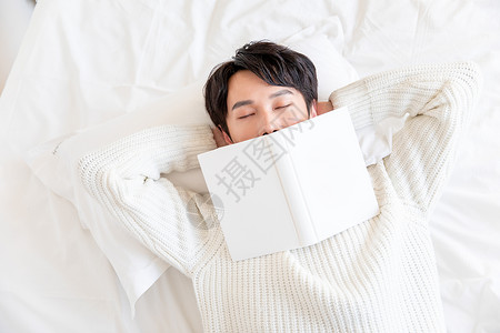 把书盖在脸上休息居家男性躺在床上休息背景