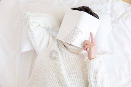把书盖在脸上休息居家男性躺在床上用书盖着脸背景