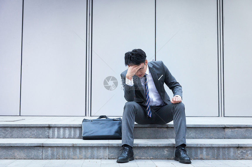坐在路边崩溃伤心的商务男性图片