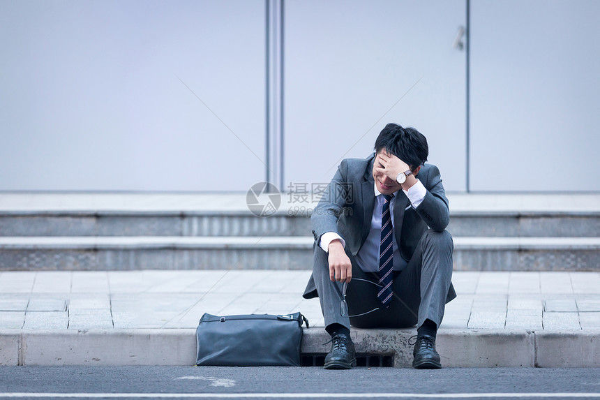 坐在路边崩溃伤心的商务男性图片