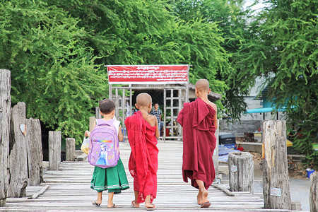 缅甸曼德勒乌本桥桥上小僧人和小学生高清图片