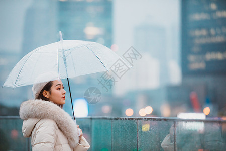 冬季女性户外下雨天撑伞看远方背景图片