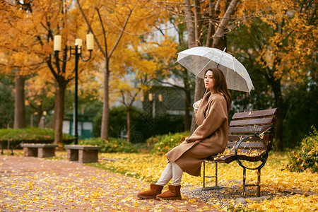 秋季雨天美女银杏落叶撑伞高清图片