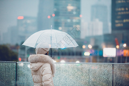 户外雨天冬季户外孤单女性撑伞的背影背景