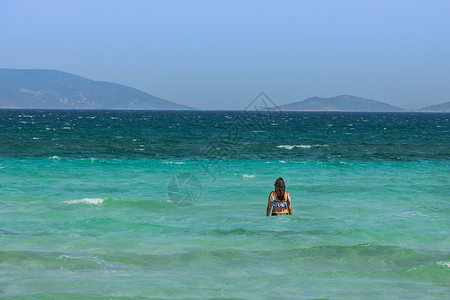 夏季游泳女性蓝色的爱琴海海滨沙滩休闲度假游泳女人背影背景
