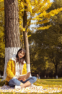 倚靠在银杏树下看书的女孩女性高清图片素材