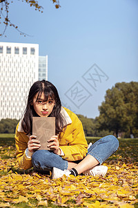 坐在满地银杏叶下的甜美女孩形象秋天高清图片素材