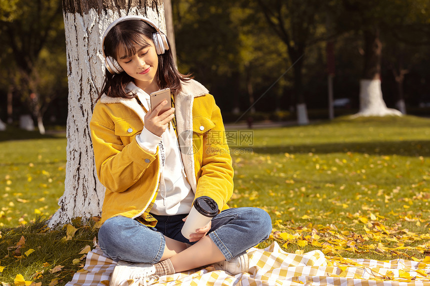 倚靠在银杏树下听音乐的女孩 图片