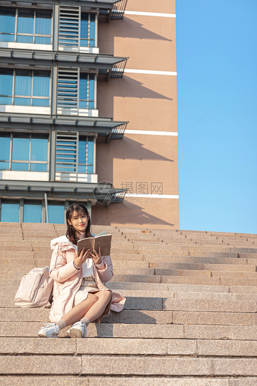 坐在台阶上阅读的女大学生图片
