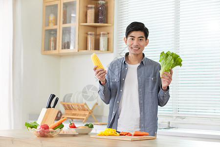 年轻男士在厨房拿蔬菜展示背景图片