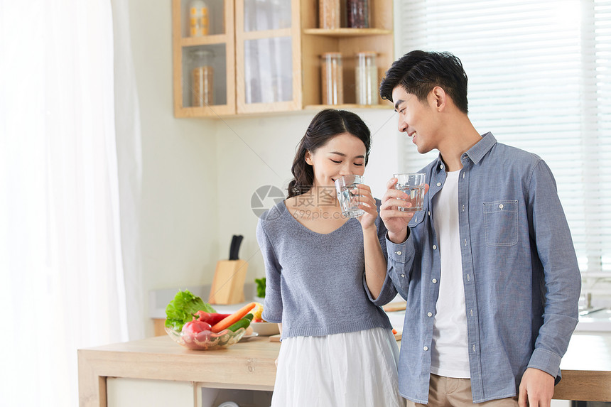 年轻情侣在厨房拿水杯喝水图片
