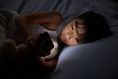 小女孩躺在床上玩手机背景
