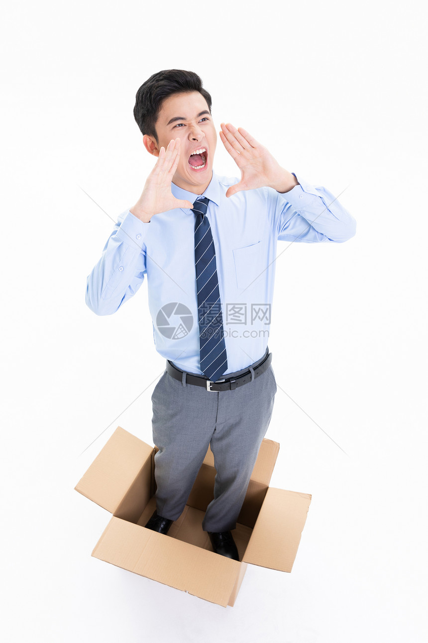俯拍站在打包箱中的商务男性呐喊图片