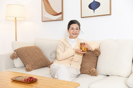 老奶奶坐沙发上手捧养生茶图片
