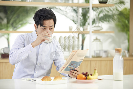年轻男士吃早餐看报纸背景图片