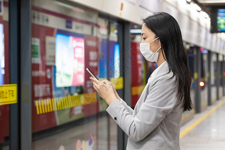 戴口罩的女性拿手机等地铁背景图片