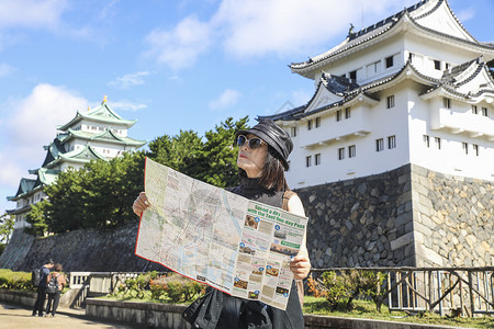 名古屋城堡在名古屋城前看旅游地图的旅行者背景