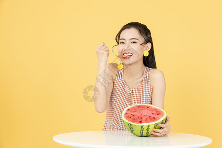 用勺子吃西瓜的甜美女性高清图片