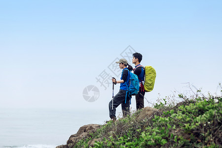 海边男女郊外站山坡上背包的男女青年背景