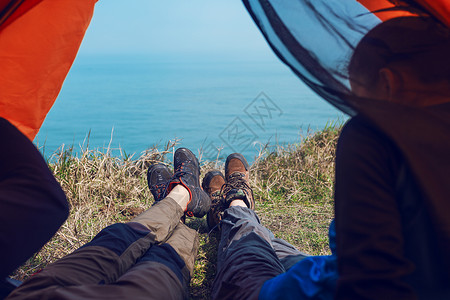 海边男女坐在海边帐篷的男女脚背景