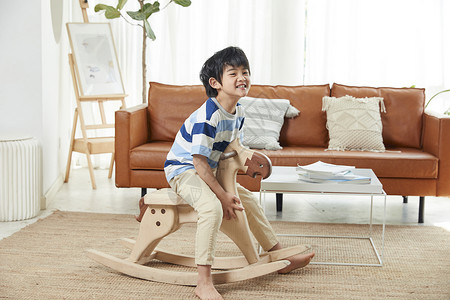 小男孩在客厅玩木马玩具背景