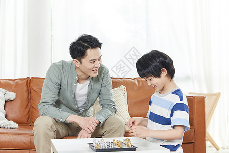 年轻爸爸陪儿子下国际象棋图片