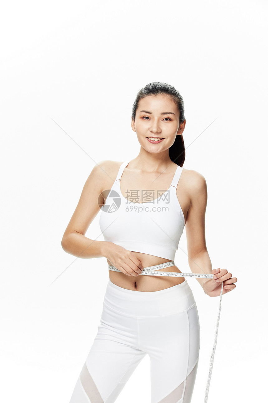 运动美女用皮尺测量腰围图片