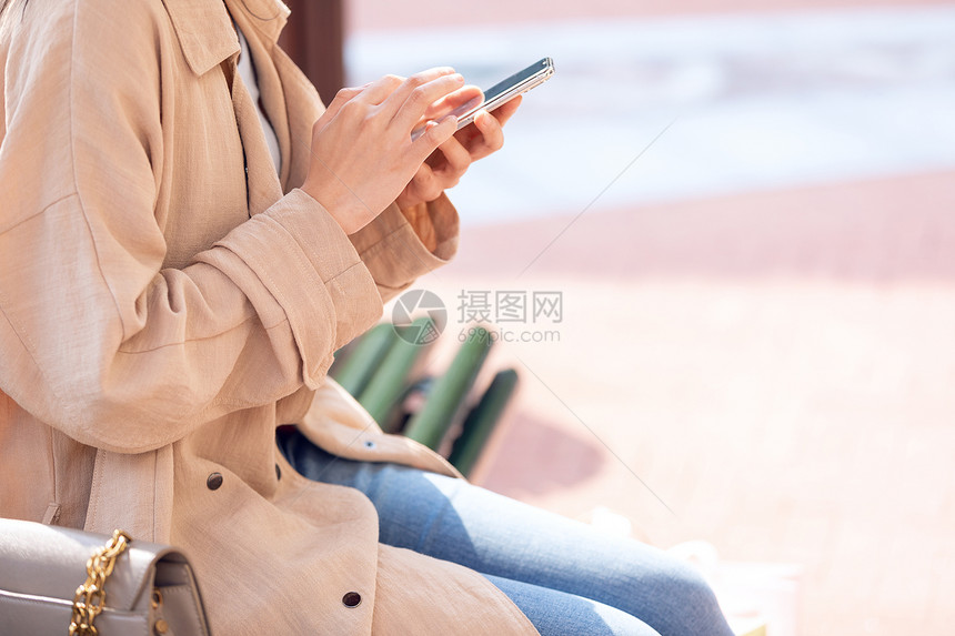 青年女性坐在椅子上休息玩手机图片