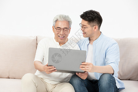 中老年父子沙发上看笔记本电脑高清图片