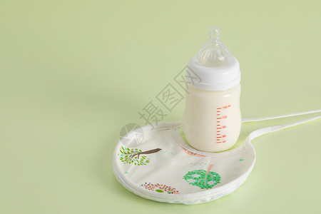 绿色橡皮婴儿奶瓶和围兜背景