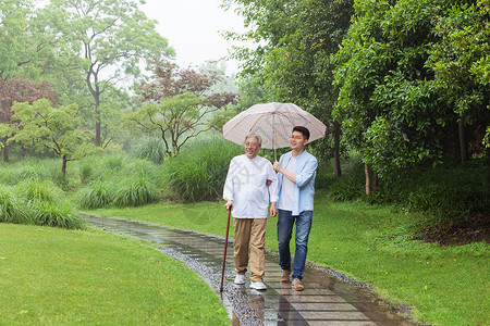 中老年父子撑伞下雨天逛公园高清图片