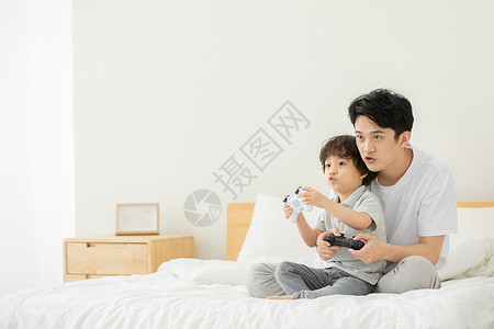 父子居家床上玩电子游戏高清图片