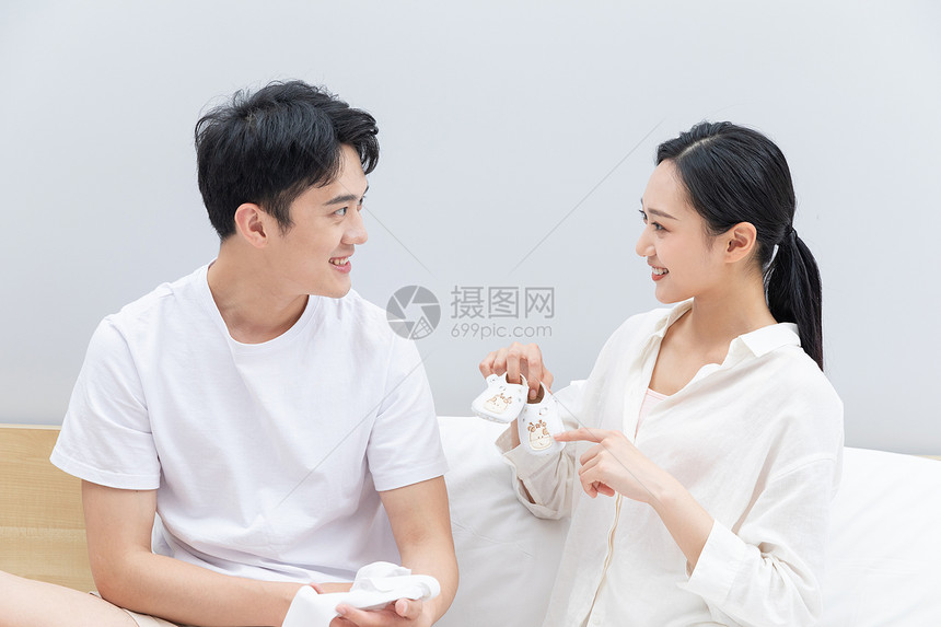 青年夫妻看着婴儿小鞋子图片